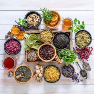 Large variety of multi colored dried tea leaves and flowers shot from above on white table