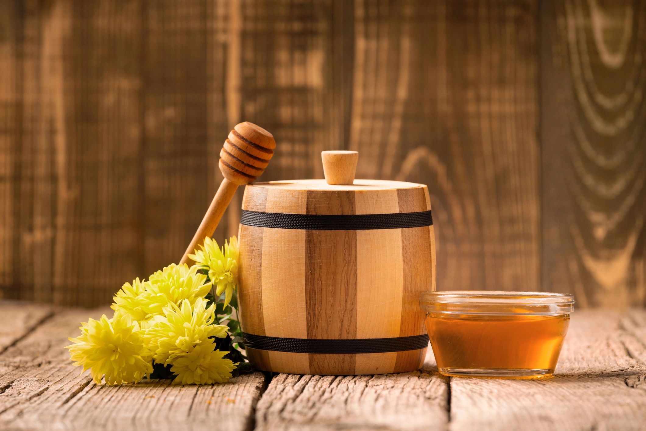 Premium raw honey in glass bowl and wooden barrel