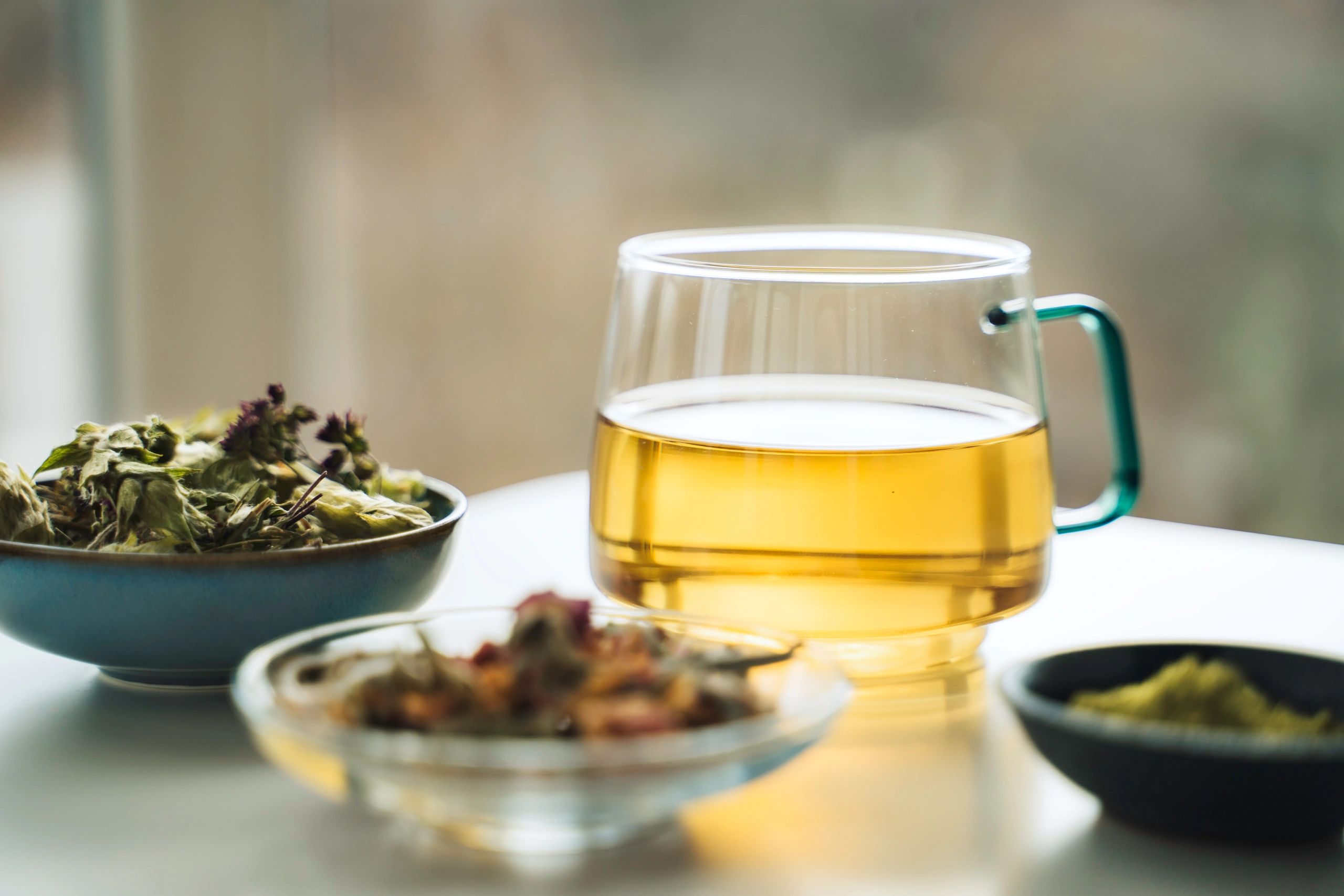 Herbal tea with dried botanicals arranged on a natural surface