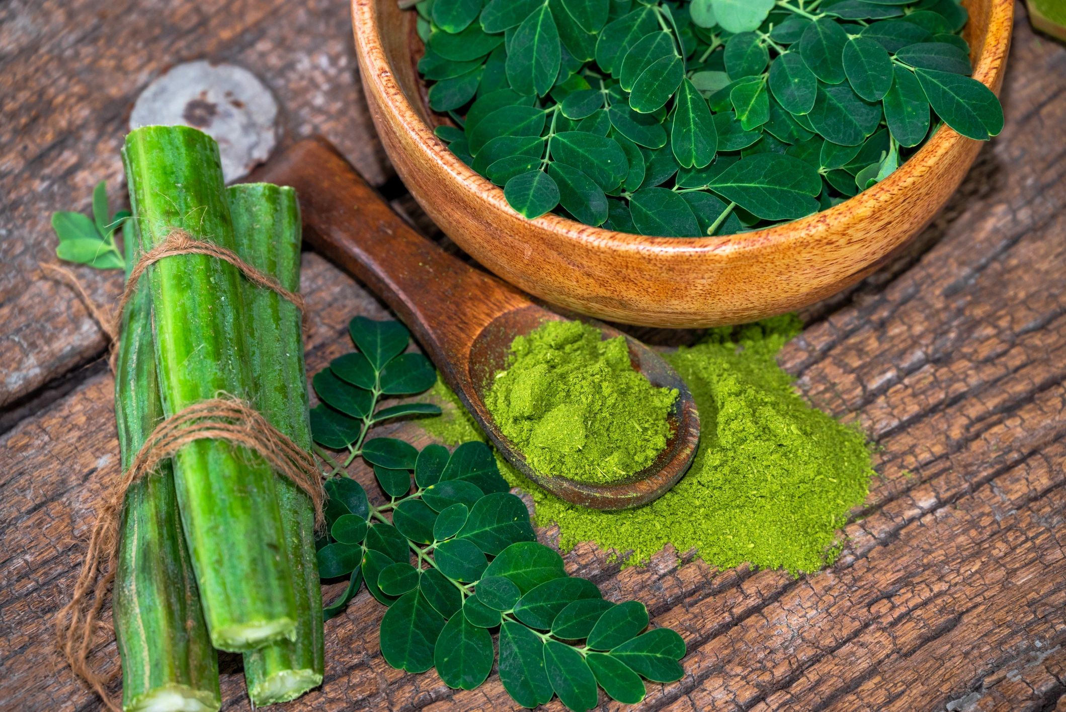 Moringa leaves and powder in a wooden bowl